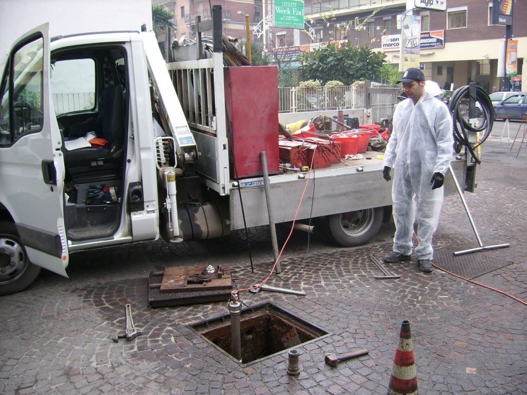 Tecnici in tuta eseguono la prova di tenuta da un pozzetto