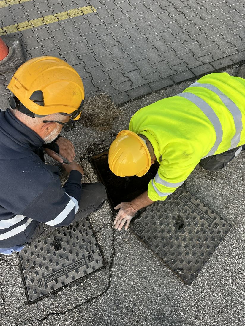 Due tecnici con casco al lavoro sui pozzetti del piazzale